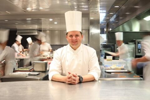 Le proposte dell’Hotel de Ville a Crissier Oltre all’eccellenza gastronomica che l’ha reso celebre, l’Hôtel de Ville di Crissier offre un ventaglio di esperienze pensate per arricchire ogni visita. Gli ospiti possono scegliere tra diverse soluzioni: una sala privata per eventi riservati, una sala dedicata a chi desidera osservare da vicino il lavoro dei cuochi, e persino un museo interno che raccoglie cimeli, fotografie, ricette e oggetti storici legati alla storia della maison. Nel dicembre 2021 è stata inaugurata la Boulangerie de l’Hôtel de Ville, una naturale estensione del ristorante. Situata a pochi passi, propone raffinate creazioni di pasticceria realizzate con la maestria dello Chef Pasticcere, che ha collaborato per due anni con lo Chef Franck Giovannini. Oltre ai dolci, la boulangerie offre un’ampia selezione di pane fresco preparato quotidianamente dal team di fornai. Nel 2023, il ristorante ha arricchito la propria offerta con una nuova cantina, progettata per custodire circa 4.000 bottiglie di vini pregiati. L’ambiente, caratterizzato da pareti scure, scaffalature in legno chiaro e un’illuminazione d’atmosfera attentamente studiata, riflette lo stile sobrio ed elegante della casa. Il sito web dell’Hôtel de Ville è moderno e dinamico: permette di acquistare buoni regalo, ricevibili comodamente a casa o via e-mail. Che si tratti di celebrare un evento in famiglia, vivere una serata romantica o condividere un’esperienza gourmet con gli amici, vengono proposti pacchetti personalizzati per soddisfare ogni desiderio. Un’altra iniziativa di rilievo è l’Accademia di Cucina, rivolta sia ai professionisti del settore sia agli appassionati. I corsi si tengono direttamente presso il ristorante, sotto la guida di Franck Giovannini e Stéphane Demarcq, e offrono un’immersione completa nel mondo dei sapori e delle tecniche culinarie, sempre in armonia con le stagioni. Infine, non manca uno shop gourmet, dove è possibile acquistare eleganti confezioni contenenti prodotti freschi da ritirare in loco: dolci e dolcetti, cioccolato, marmellate, miele, vini, champagne, condimenti e altre delizie selezionate. 